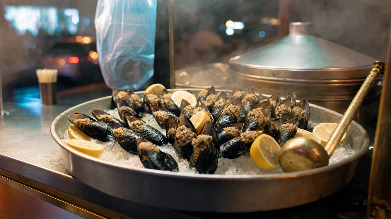Buz üzerinde dizilmiş midye dolma tepsisi, yanında limon dilimleri