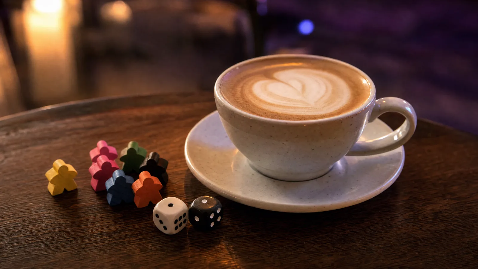 Kalp desenli latte, yanında renkli meepleler ve iki zar