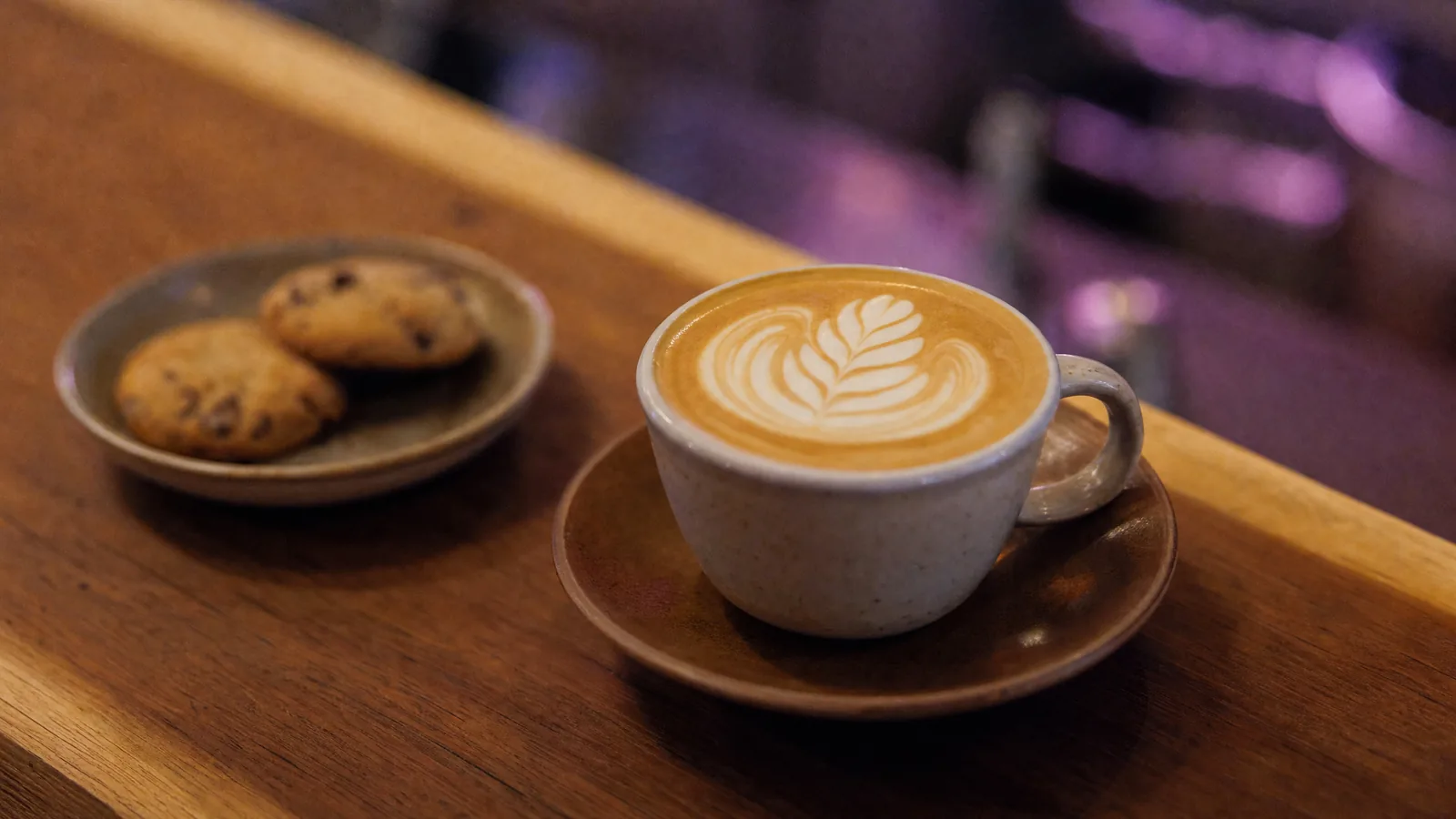 Yaprak desenli latte, yanında kurabiye tabağı